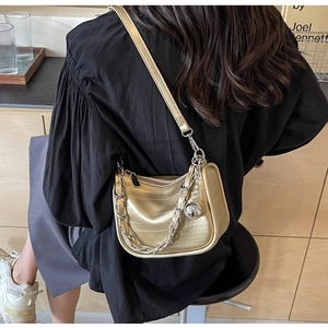 Détail du sac en cuir doré champagne avec chaîne argentée et pendentif boule polie