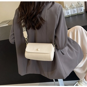 Detail of cream-colored textured crossbody bag with geometric wide fabric strap