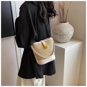 Detail of cream leather and straw bucket bag with elegant golden twist lock closure