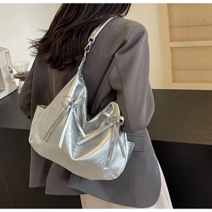 Side view of a silver metallic tote bag featuring bow details and a vertical zipper design