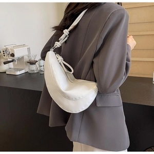 Close-up of knotted shoulder strap and smooth PU leather of white crescent bag