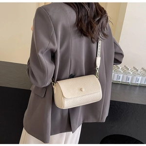 Detail of cream grained leather cylinder bag with wide geometric woven strap