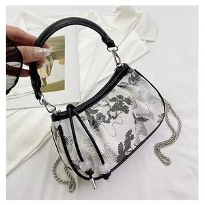 Detailed view of white fabric handbag featuring black ink pine and bird embroidery