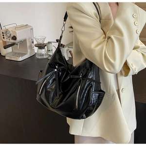 Detail of black lychee texture bucket bag with dual zippers and decorative bow detail