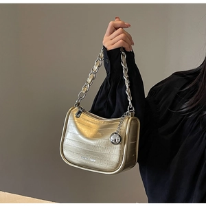 Détail du sac doré texture crocodile avec chaîne argentée et pendentif métallique
