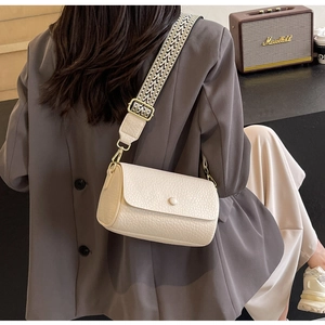 Detail of off-white crossbody bag featuring a wide black and white woven strap