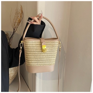 Close-up of woven straw bucket bag with leather trim and gold twist lock closure