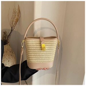 Detail of woven straw bucket bag with beige leather trim and gold twist lock closure