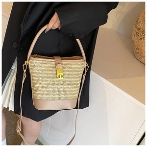 Detail of woven straw bucket bag with khaki leather handles and golden metal twist lock