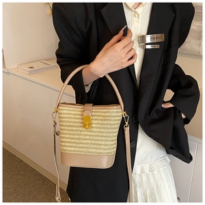 Close-up of beige woven bucket bag featuring brown leather trim and golden CD metal clasp