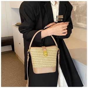 Detail of woven straw bucket bag with brown leather trim and golden metal lock clasp
