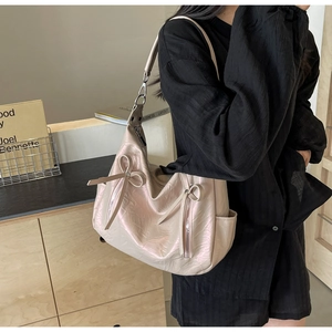 Close-up of pink hobo bucket bag featuring decorative bows and side zippers