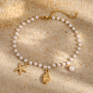 Marine style stainless steel pearl anklet with gold starfish and shell charms on sand