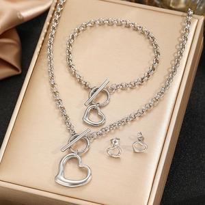 Silver hollow heart jewelry set with necklace bracelet and earrings on gold display