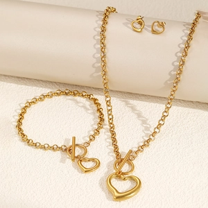 Close-up of gold hollow heart jewelry set with OT toggle clasp on a textured surface