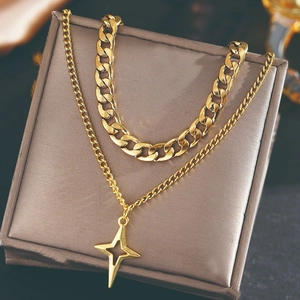 Double-layered gold punk star pendant necklace with cuban chain on a brown jewelry display