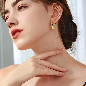 Primo piano di orecchini a cuore in oro 18k lucido indossati da una modella per un look chic