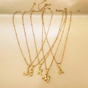 Macro view of five 18k gold plated stainless steel initial balloon letter necklaces