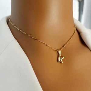Close-up of gold stainless steel necklace with a polished K letter pendant on a model