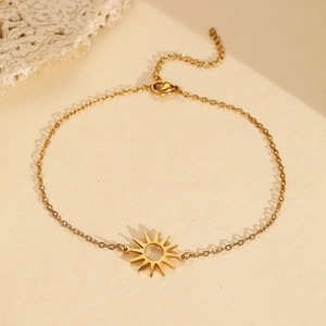 Detail view of the hollow sun pendant on a dainty gold stainless steel chain bracelet