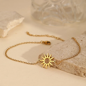 Elegant gold hollow sun pendant bracelet with minimalist chain on natural stone background