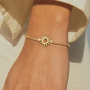 Detail of a minimalist gold sun charm bracelet with a delicate O-chain on a woman wrist
