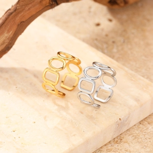 Close-up of geometric hollow open rings in gold and silver finish on stone display