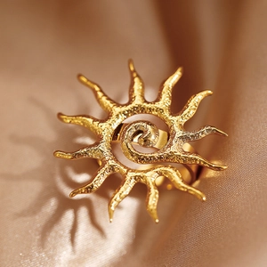 Golden sunburst geometric open ring with hammered texture on a champagne silk background