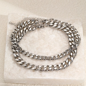 Layered silver curb chain anklet set displayed on natural white stone for summer beach style