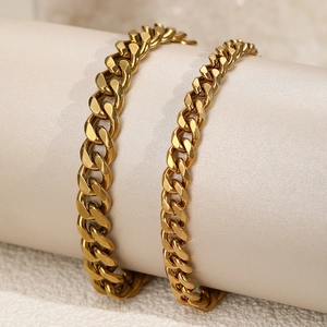 Detail of layered gold Cuban link anklets wrapped on a prop for beach fashion
