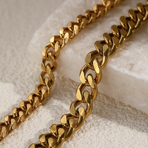 Macro close-up of golden Cuban link chain with polished finish on white mineral background