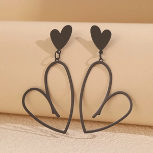 Boucles d'oreilles double cœur noir mat suspendues sur un support à bijoux cylindre