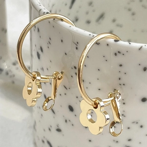 Detailansicht der goldene Blumenohrringe an einer Tasse im minimalistischen Design
