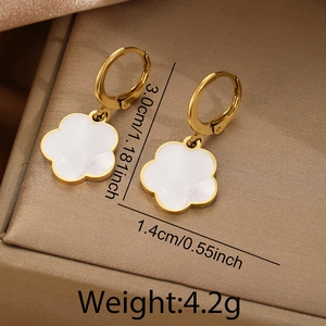 Close-up of golden flower earrings with white mother of pearl petals on a silk background