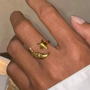 Detail of adjustable gold sun and moon ring with star design worn on a finger