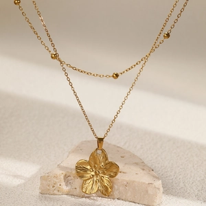 Macro d'un collier double rang fleur dorée avec pétales gaufrés sur base de pierre
