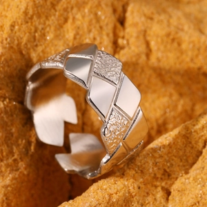 Macro detail of silver geometric pleated ring with textured and polished finish surface