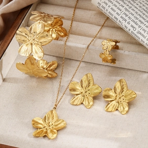 Détail d'un ensemble de bijoux fleurs dorées avec texture brossée mate dans un coffret