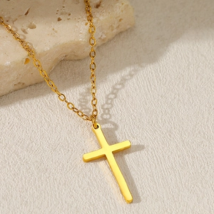 Collana con croce in acciaio inossidabile dorato da donna su sfondo di pietra naturale