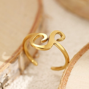 Macro shot of gold adjustable letter ring on wood base with a sleek streamlined design