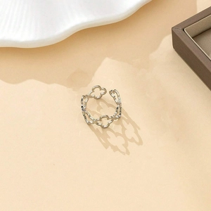 Close-up of adjustable silver hollow clover ring on a minimalist tray background