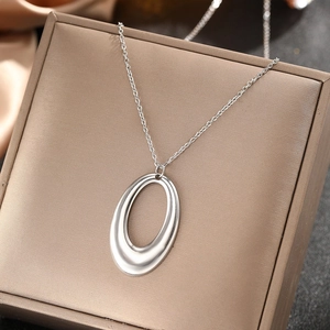 Polished silver stainless steel necklace with hollow oval pendant on a jewelry box