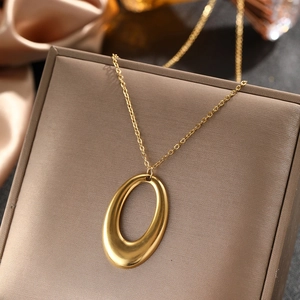 Minimalist gold hollow oval geometric pendant necklace displayed on a leather jewelry box
