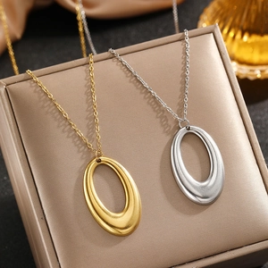 Close-up of gold and silver geometric oval pendant necklaces on luxury silk packaging