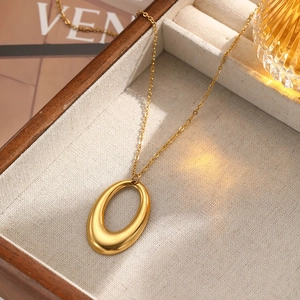 Close-up of a gold hollow oval pendant necklace on a linen jewelry display box