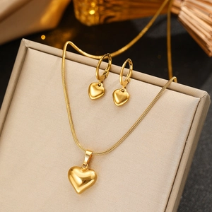 Polished gold heart pendant necklace and hoop earrings jewelry set on a beige display box