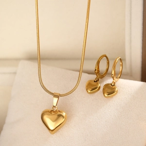 Detailed macro view of golden heart pendant necklace and earrings in a velvet gift box