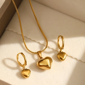 Detailed close-up of polished gold heart necklace and matching earrings set