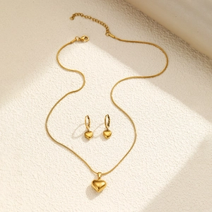Detailed view of heart pendant necklace and matching earrings set in gold stainless steel