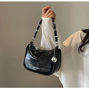 Détail du sac en cuir gaufré brillant noir avec chaîne argentée et pendentif boule
